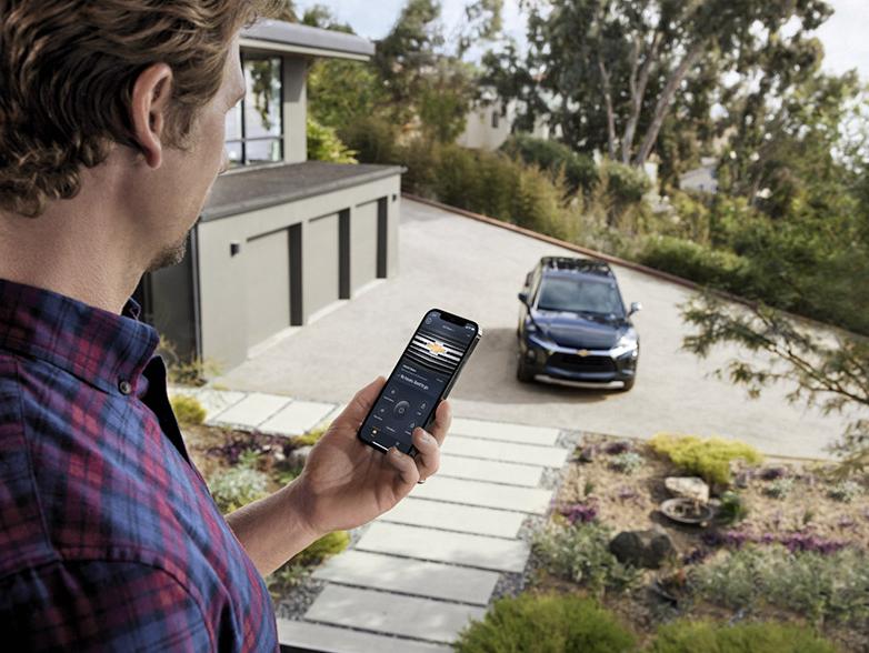 Man holding phone with myChevrolet App and Chevy in background Man holding phone with myChevrolet App and Chevy in background