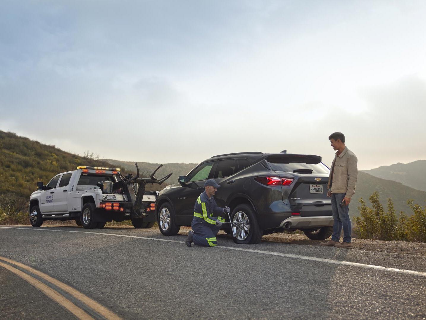 Truck and Equinox on road surrounded with mountains, And worker helping to tow car Truck and Equinox on road surrounded with mountains, And worker helping to tow car