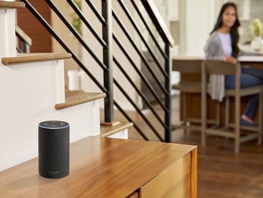 Woman at table in background with amazon alexa device activated in foreground
