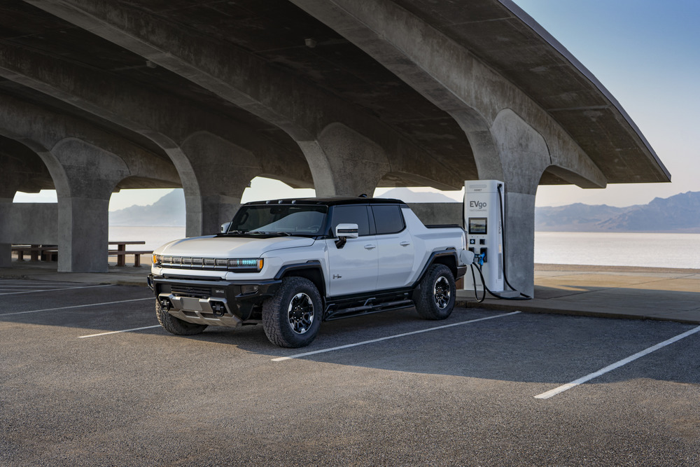 2022 GMC HUMMER EV Edition 1 Pick-Up Truck in Interstellar White; Connected to EVGo Charging Station; 3/4 Drivers side Front; Mountains and water in background