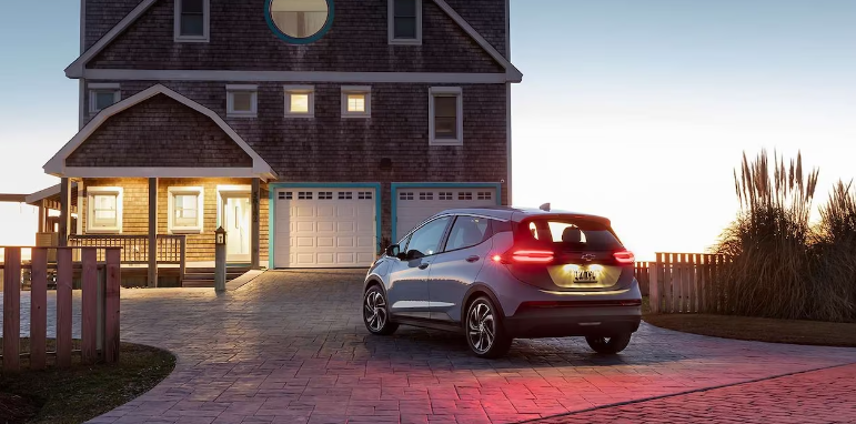 A 2023 Chevy Bolt EV parked in a driveway at sunset