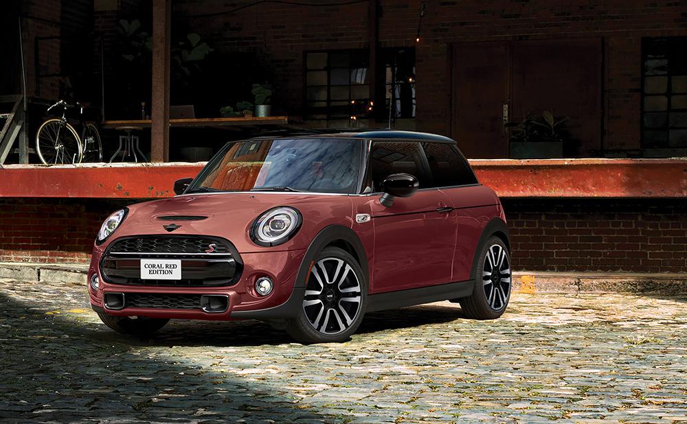 The MINI COOPER HARDTOP CORAL RED EDITION parked on a cobblestone road.
