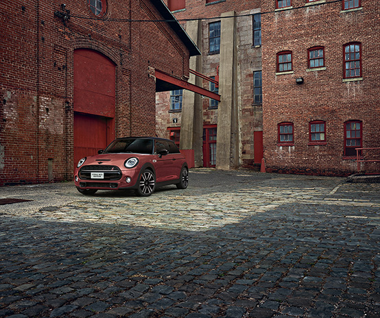 The MINI COOPER HARDTOP CORAL RED EDITION parked on a cobblestone road.