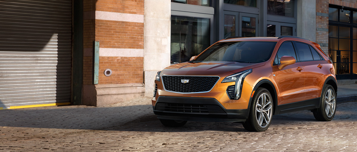 An orange 2019 Cadillac XT4 modeled in front of a brick building