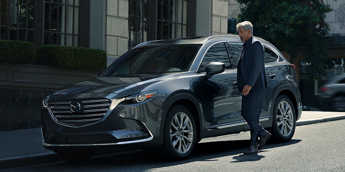 A man approaching a gray Mazda CX-9