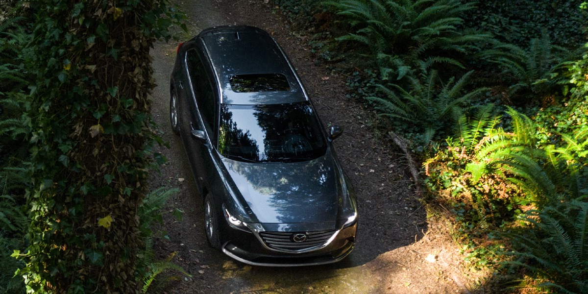A gray Mazda CX-9 driving down a dirt road