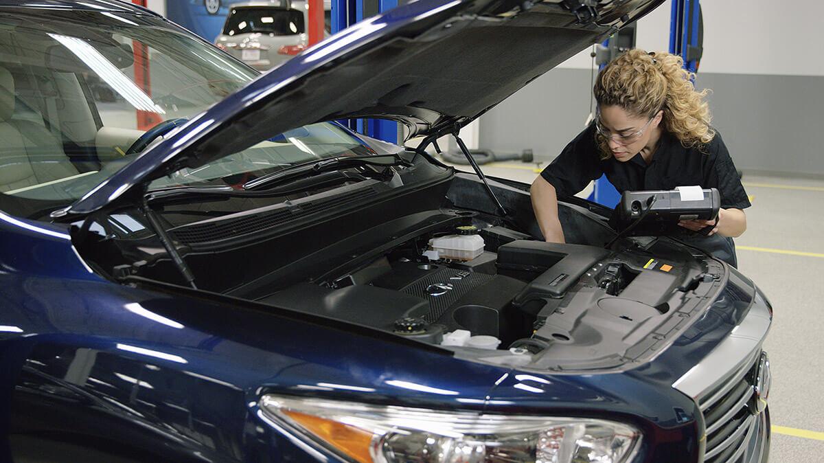 Infiniti technician working on a vehicle. Infiniti technician working on a vehicle.