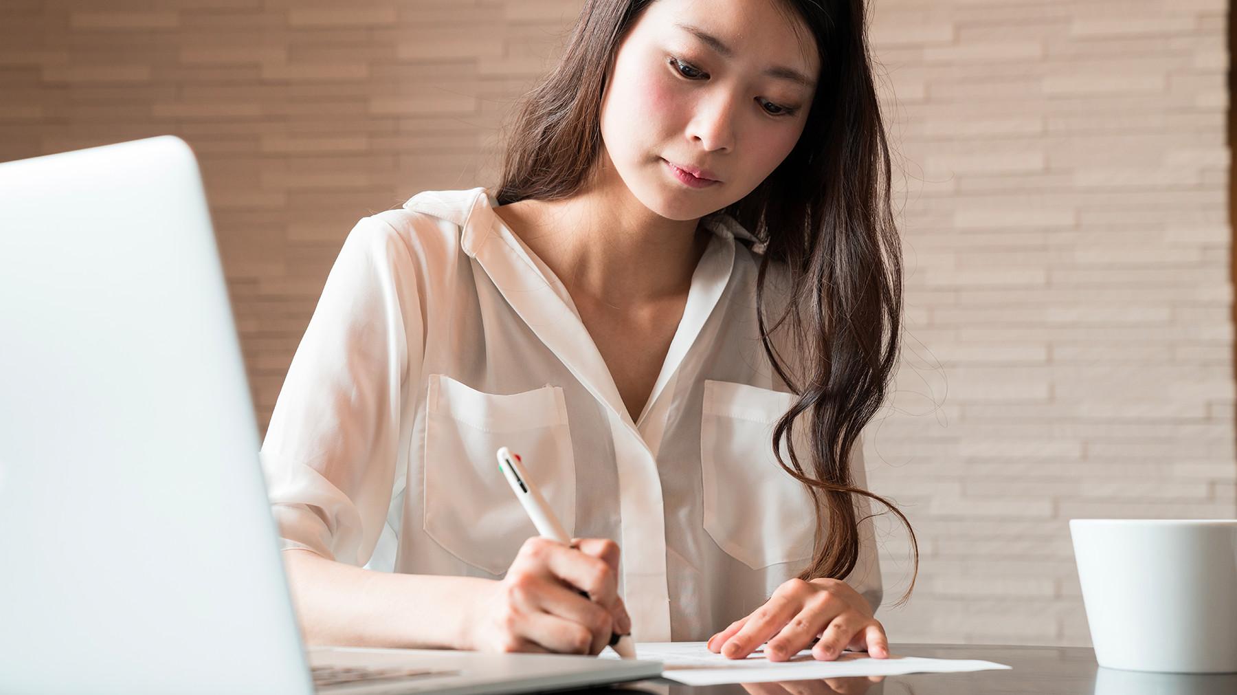 Women applying to job on computer and writing on paper Women applying to job on computer and writing on paper