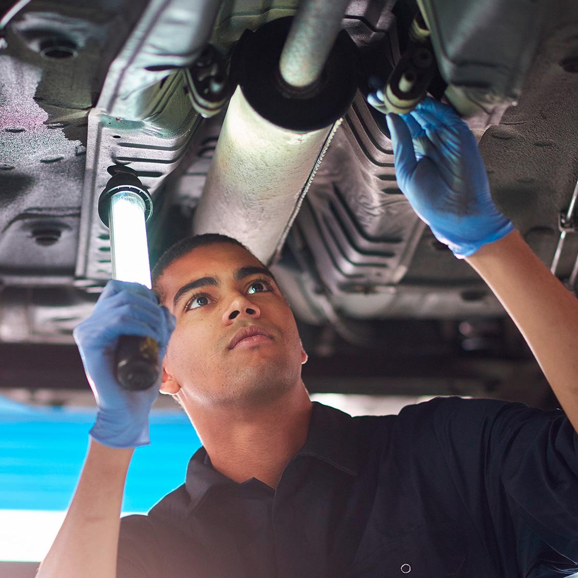 Service technician under vehicle with light