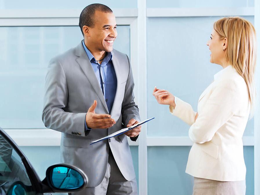 Woman Chatting with Salesperson in Dealership Showroom