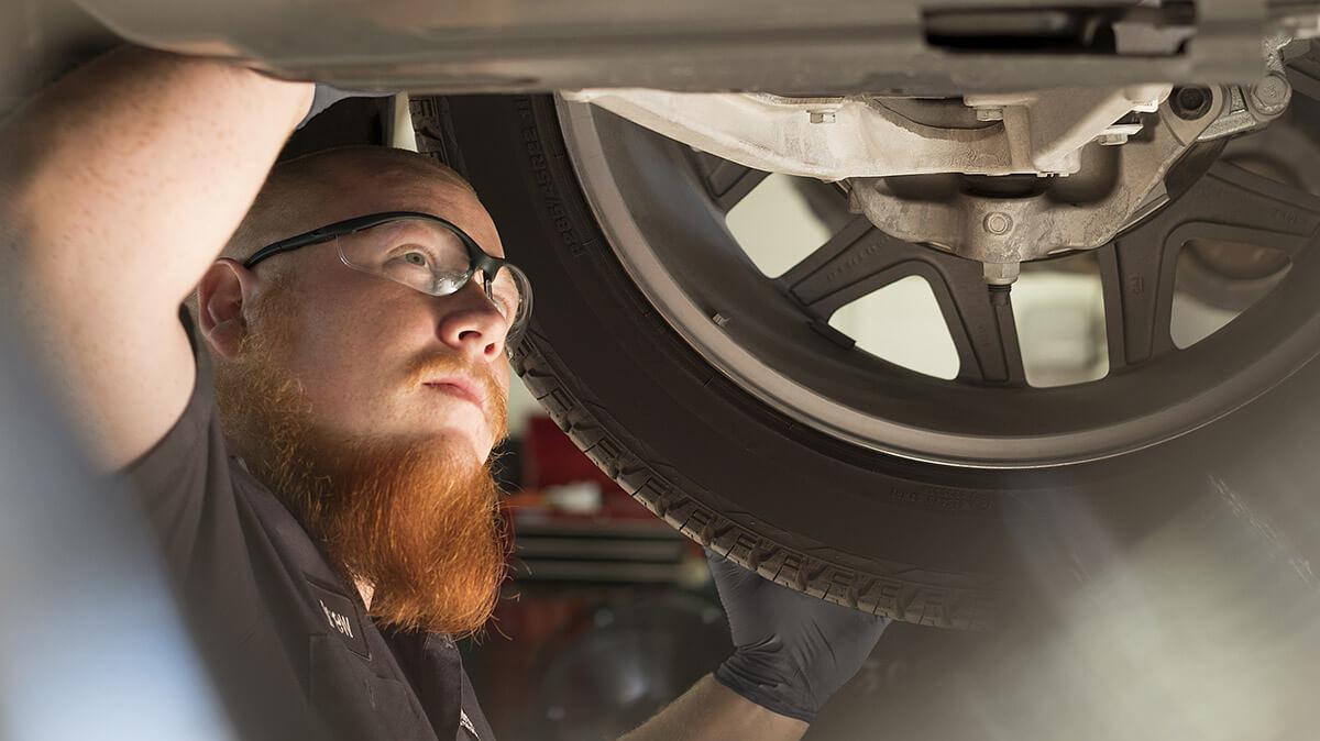 A mechanic working under a vehicle on a lift. A mechanic working under a vehicle on a lift.
