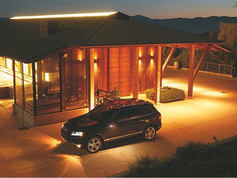 Black VW Toureg parked in driveway at night time.