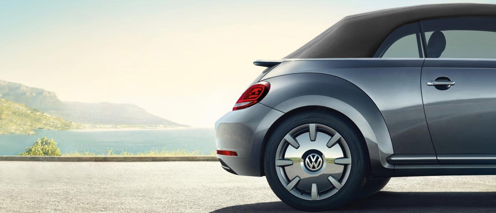 VW Bug parked next to beach.