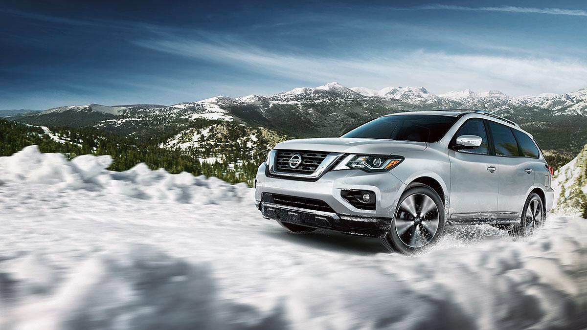 The 2018 Nissan Pathfinder driving on a snowing mountain road.