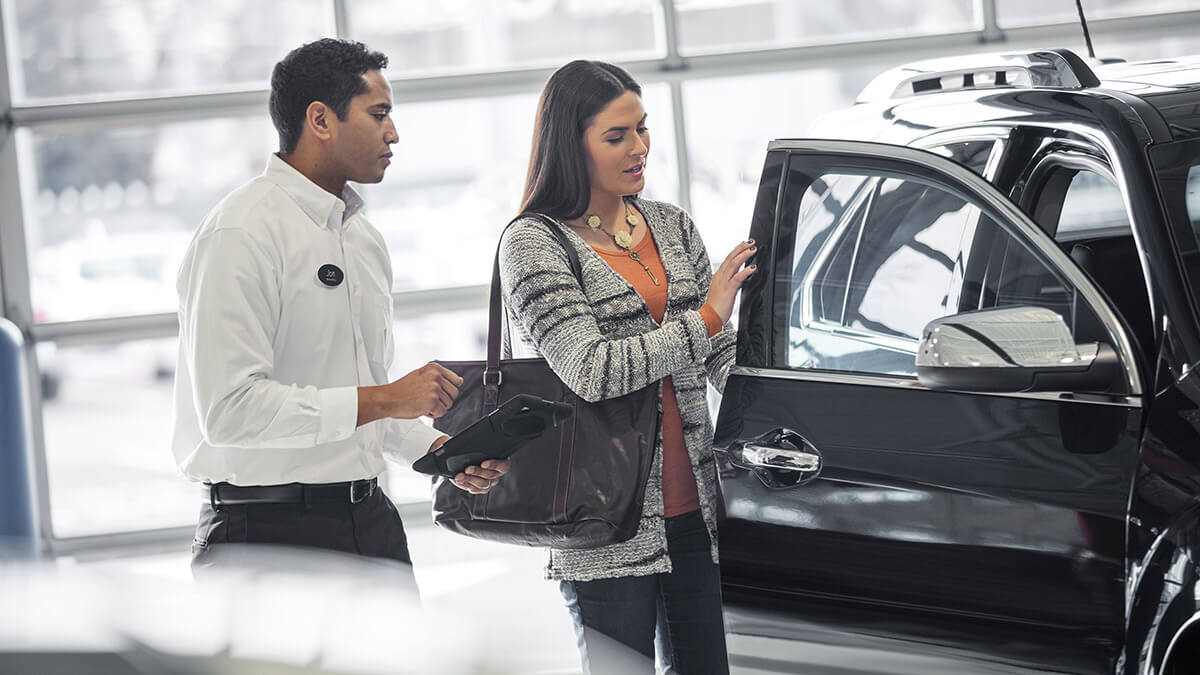 Car salesman showing a woman a new vehicle.