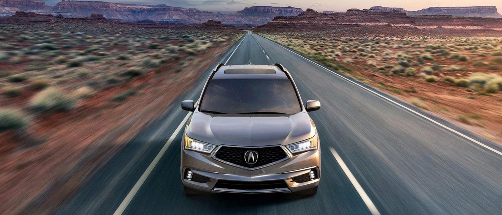 A silver Acura MDX driving on a desert highway at dusk. A silver Acura MDX driving on a desert highway at dusk.