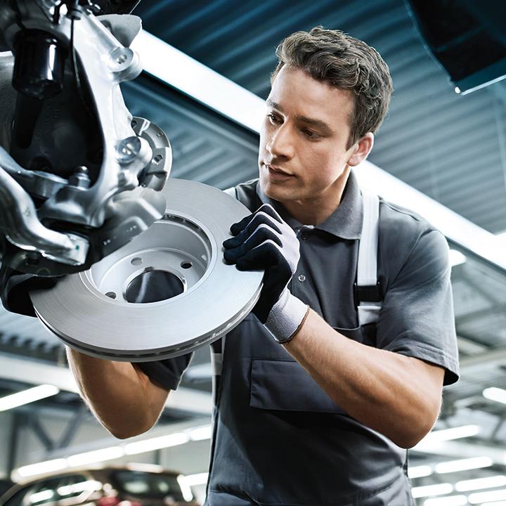 A BMW certified service technician working on a vehicle's brakes.