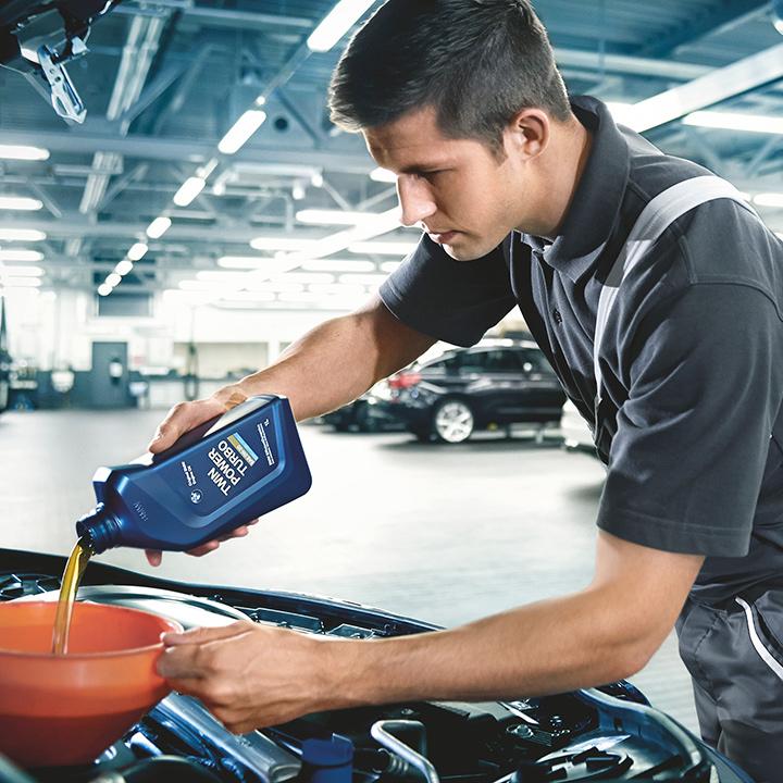 A BMW certified service technician performing an oil change.