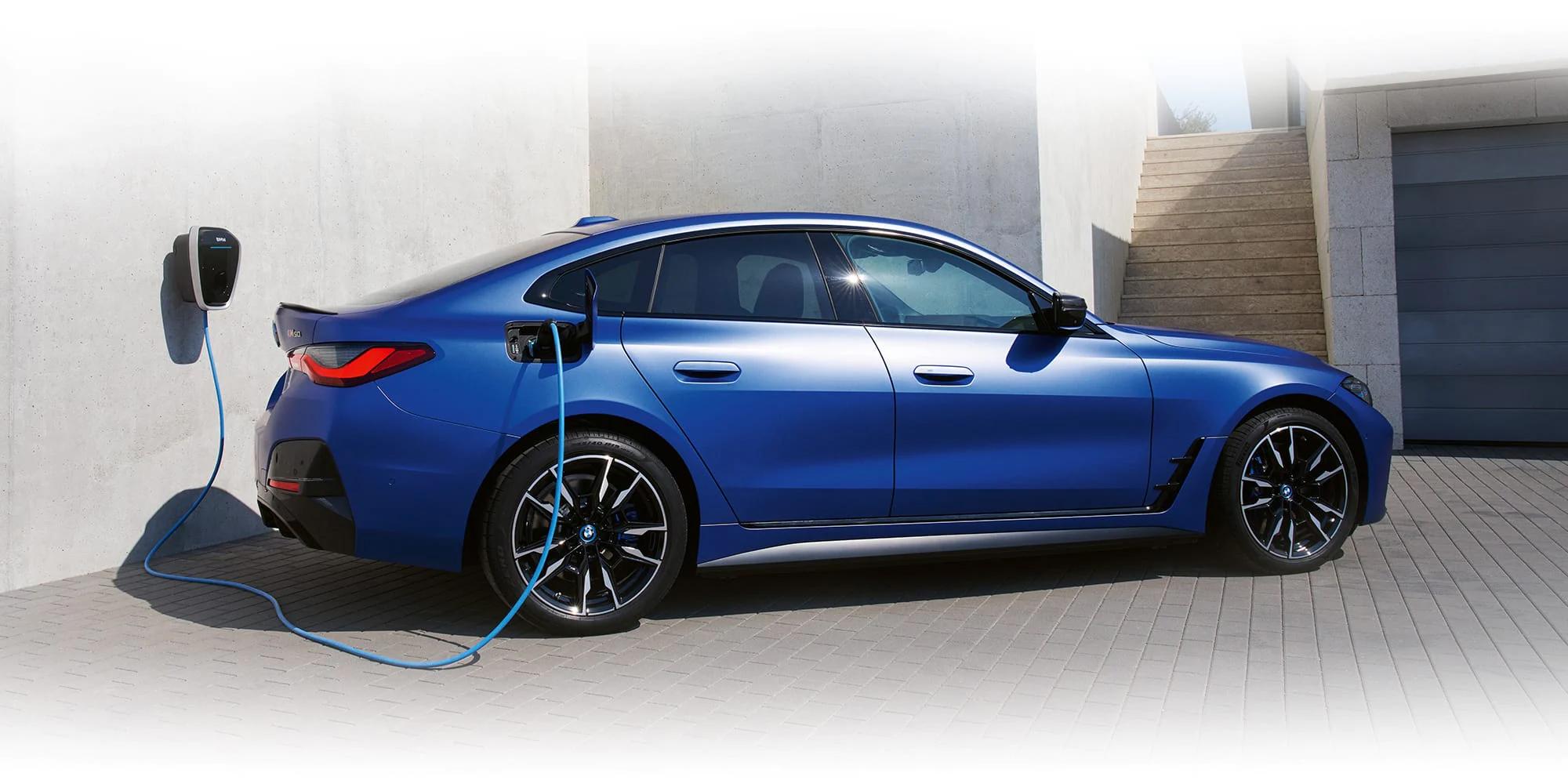 The BMW i4 charging beside a house