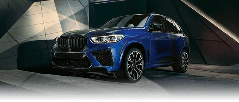 A blue BMW X5 M parked in a modern courtyard.