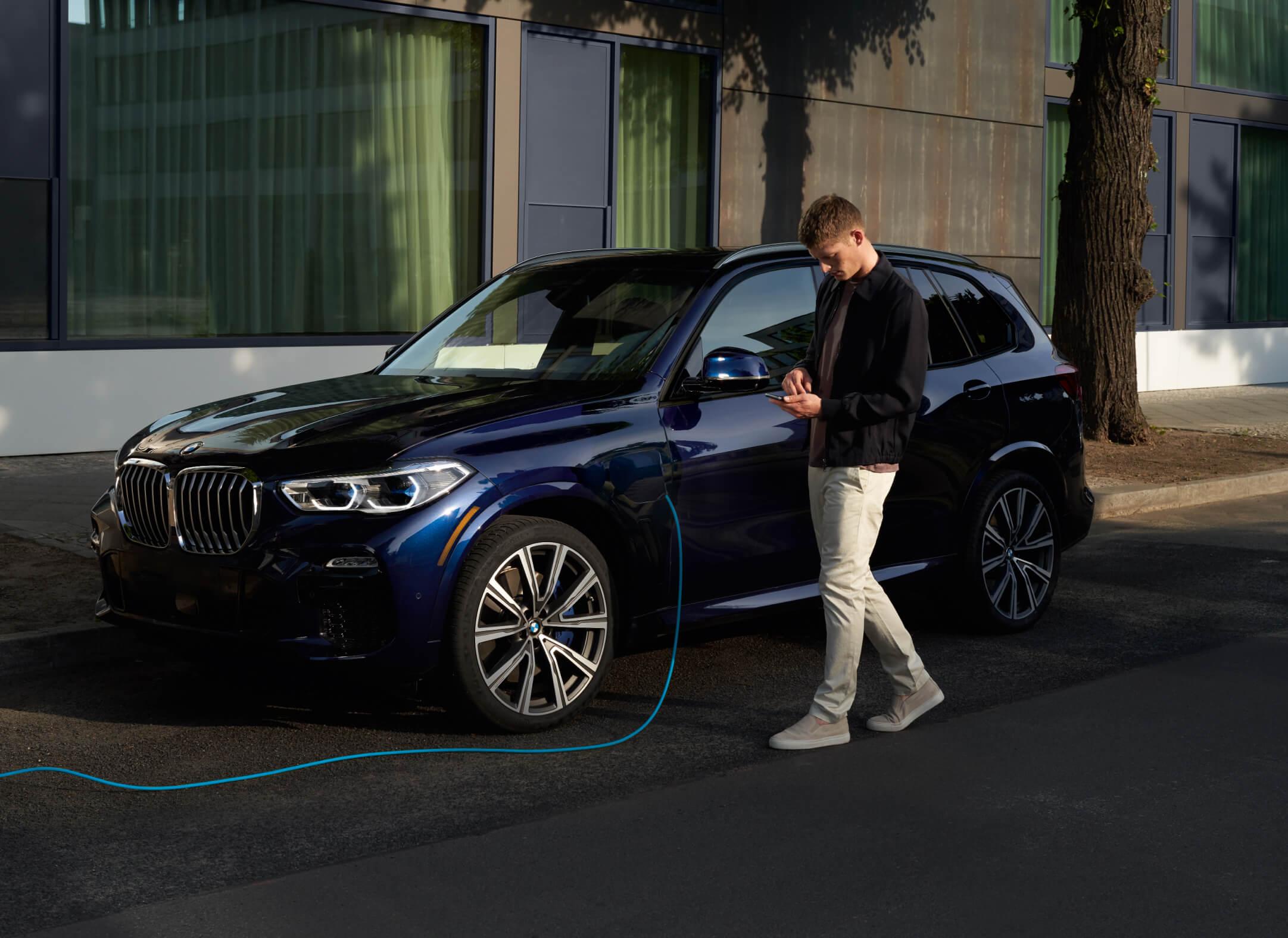 Man using mobile while charging EV