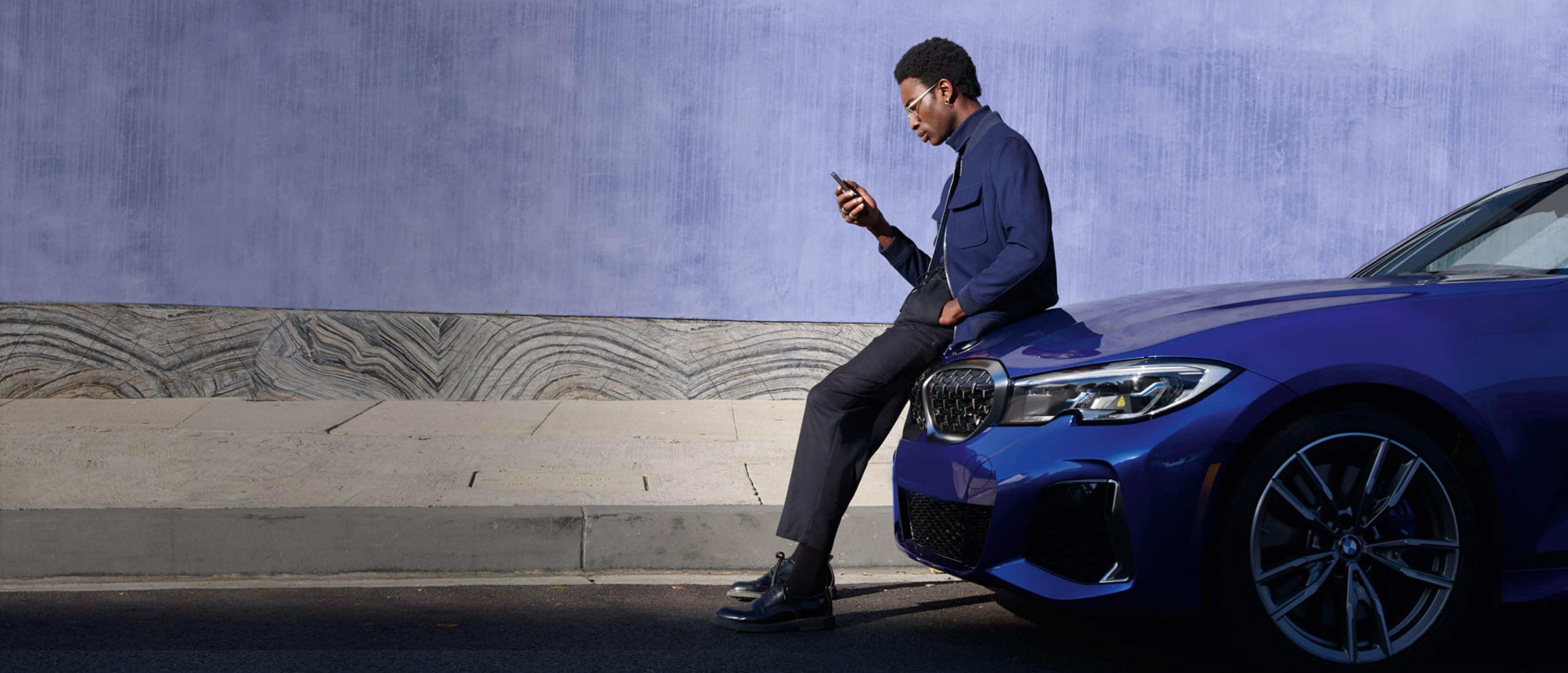 Man seating on BMW and browsing on mobile