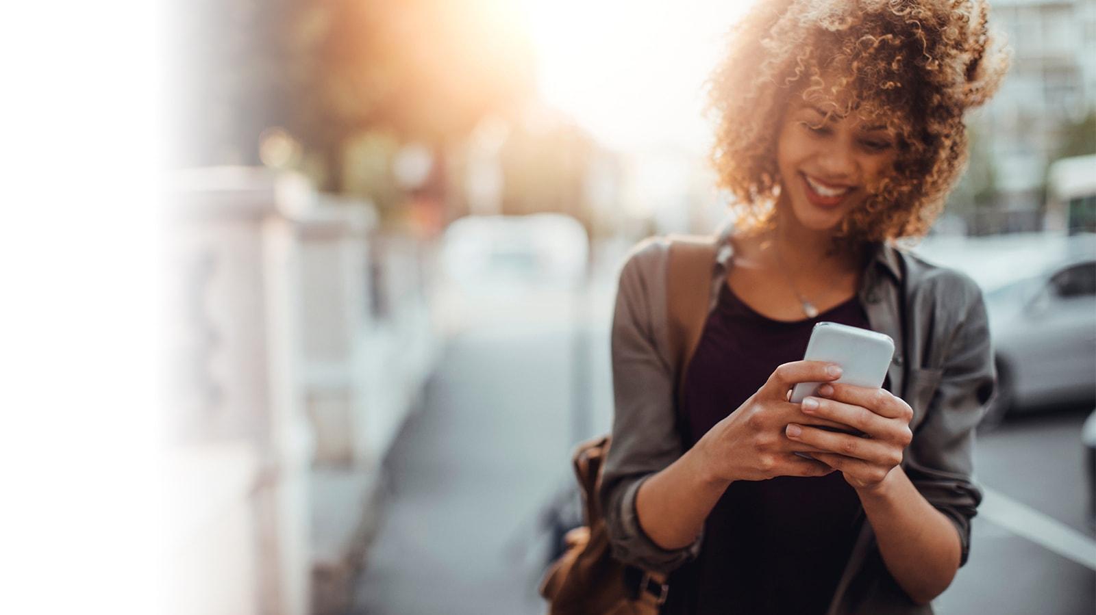 Woman using her smart phone while walking