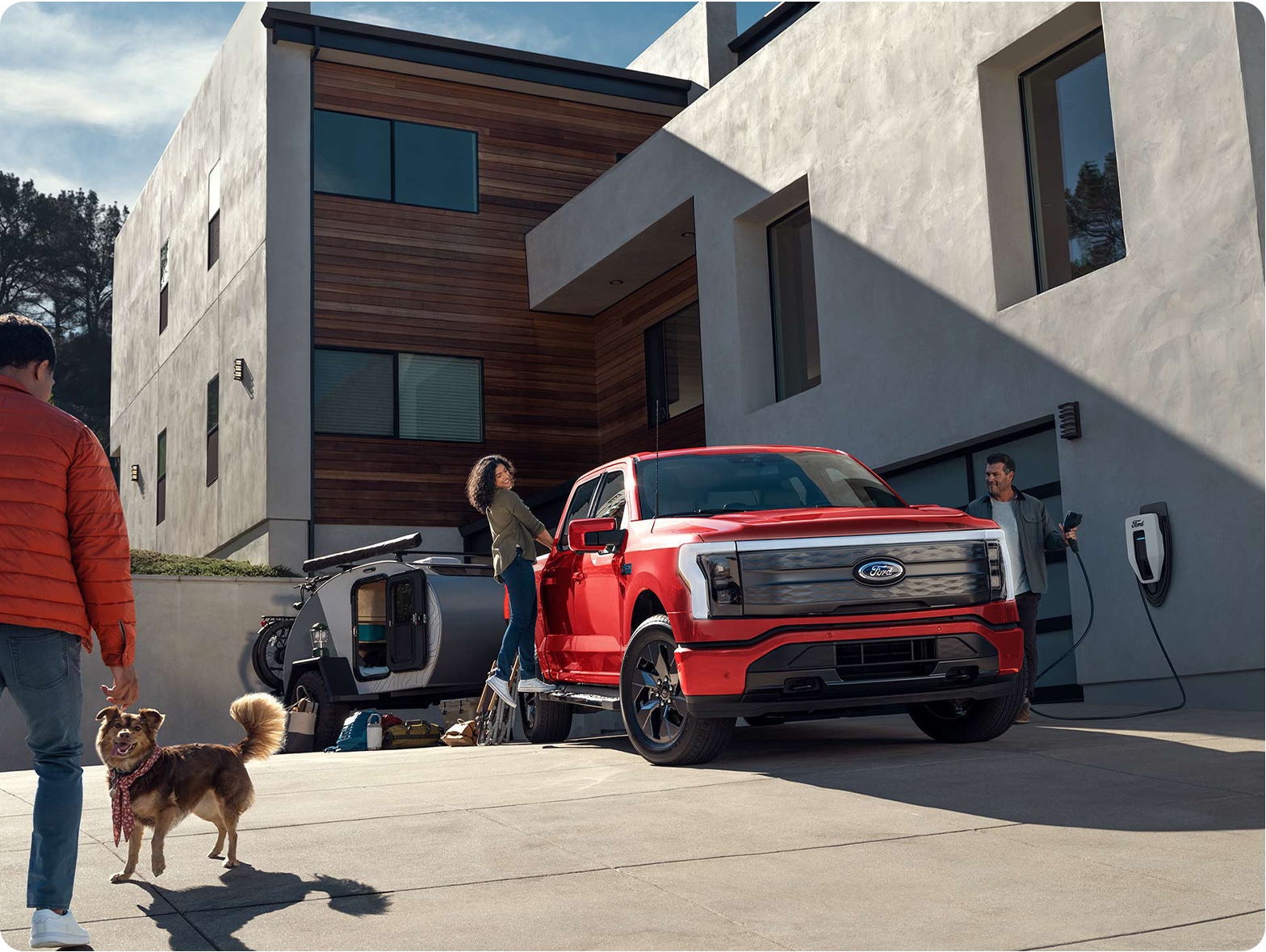 A couple talks to a neighbor as one of them unplugs their F-150 Lightning® from a home charging station