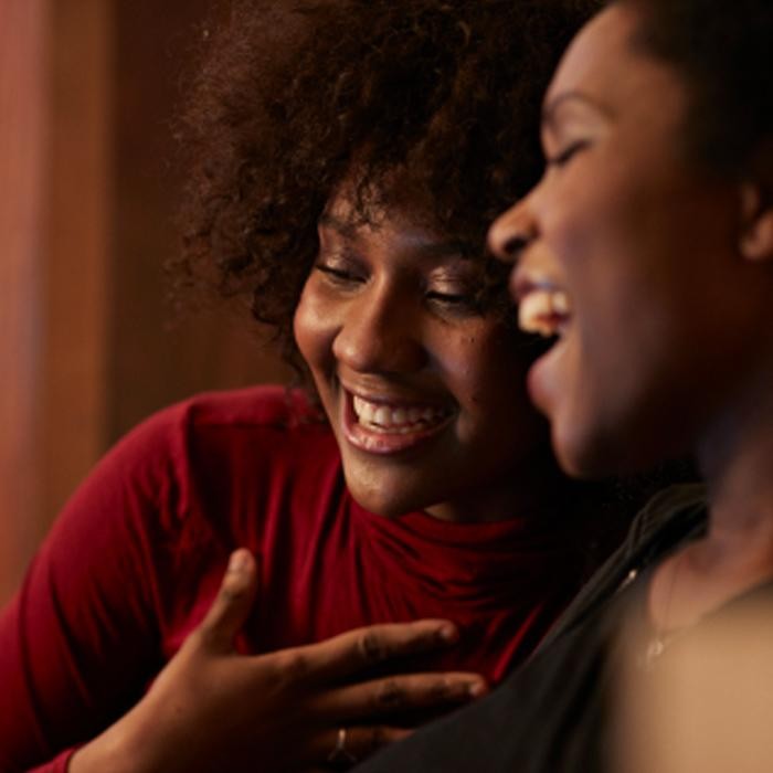 Two woman smiling and hugging. 