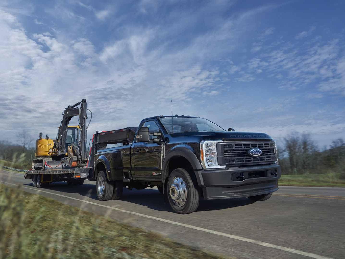 A diesel Super Duty® truck towing an excavator on a two lane road