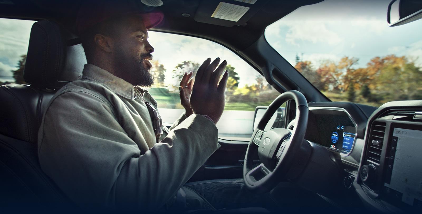 Man removing hands from the steering wheel while using BlueCruise on a sunny day