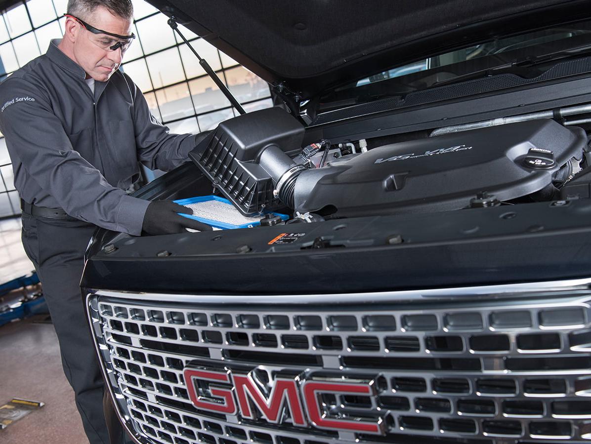 GMC certified service mechanic replacing a vehicle's air filter