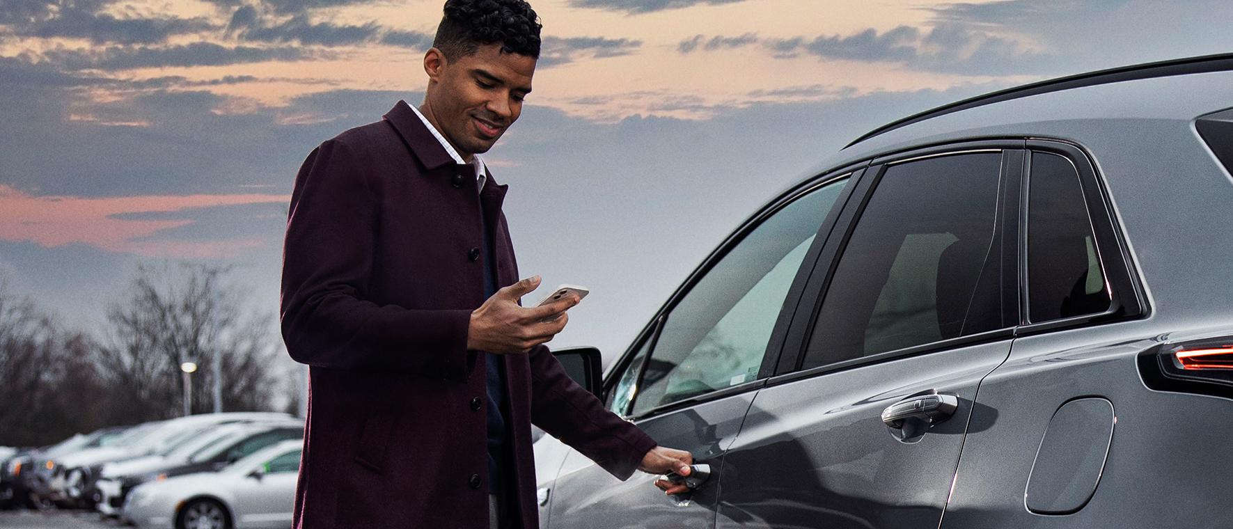 Man looking at his phone opening his car door.