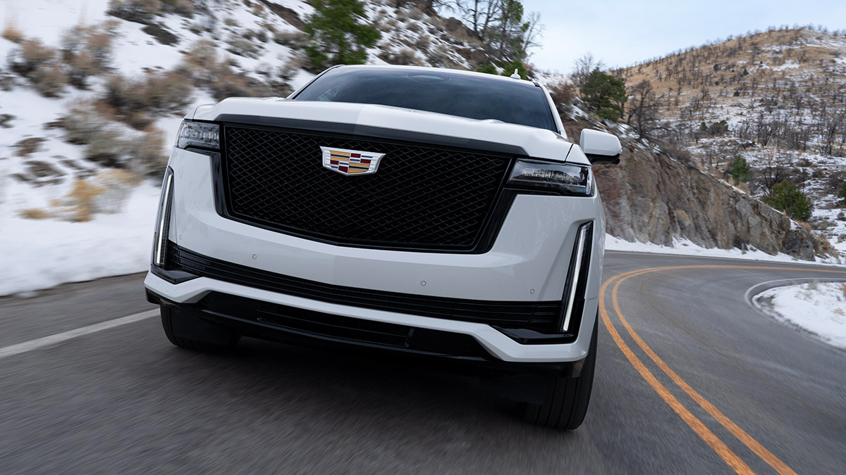 Front grille of a white 2022 Escalade driving down the highway.