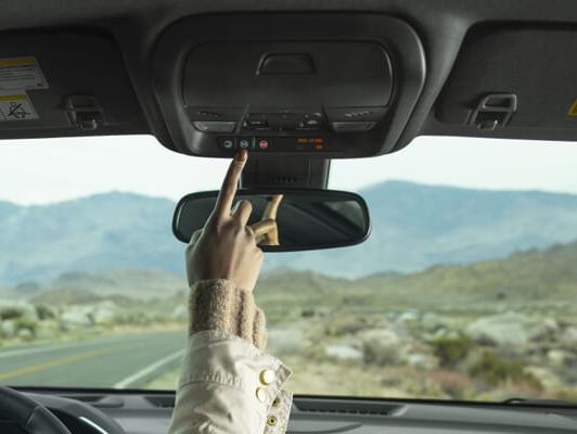 woman pushing onstar button on rear view mirror in desert woman pushing onstar button on rear view mirror in desert