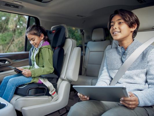 2 children with tablets in the back of a GMC 2 children with tablets in the back of a GMC