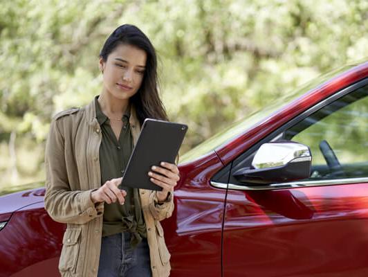 Woman outside red car on ipad Woman outside red car on ipad