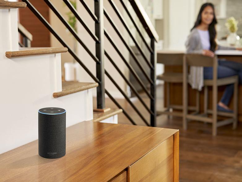 Woman at table in background with amazon alexa device activated in foreground Woman at table in background with amazon alexa device activated in foreground