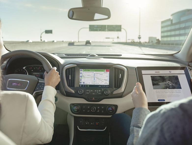 Woman driving using on screen navigation and man on tablet in passenger seat Woman driving using on screen navigation and man on tablet in passenger seat