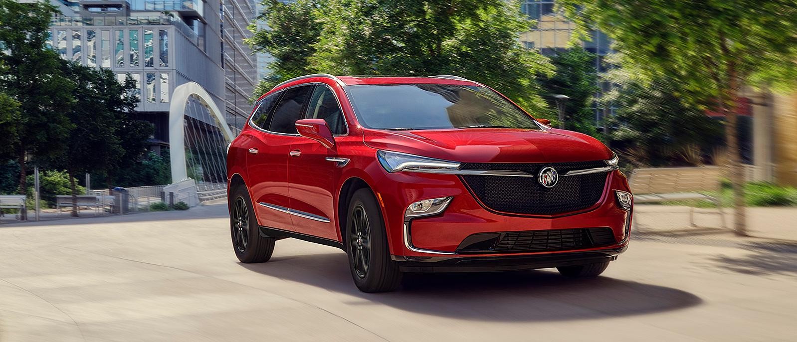 A 2023 Cherry Red Enclave driving in the city.