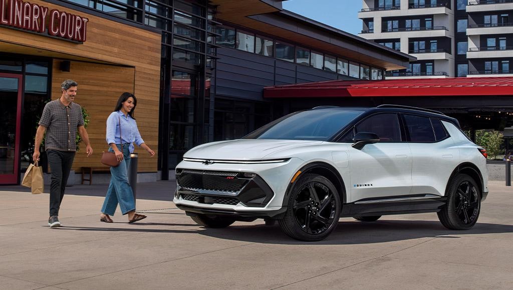 White 2025 Equinox EV with a couple walking by