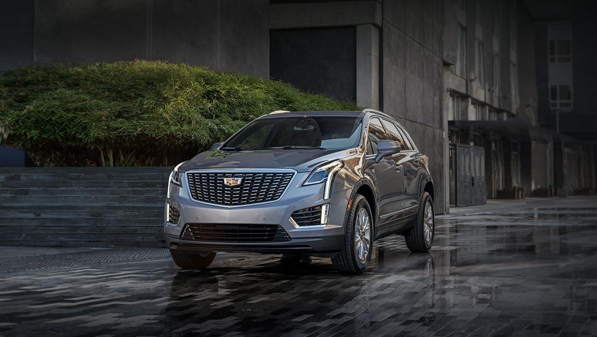 A white 2022 Cadillac XT5 in front of an condo building.