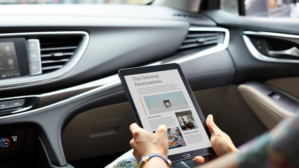 A lady holding a tablet seated on a front passenger seat