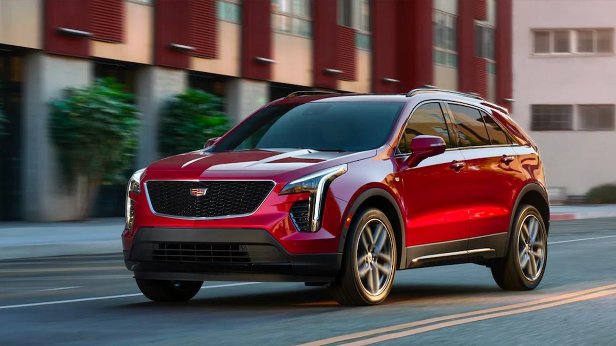 A blue 2022 Cadillac XT4 parked at a lakefront with mountains.