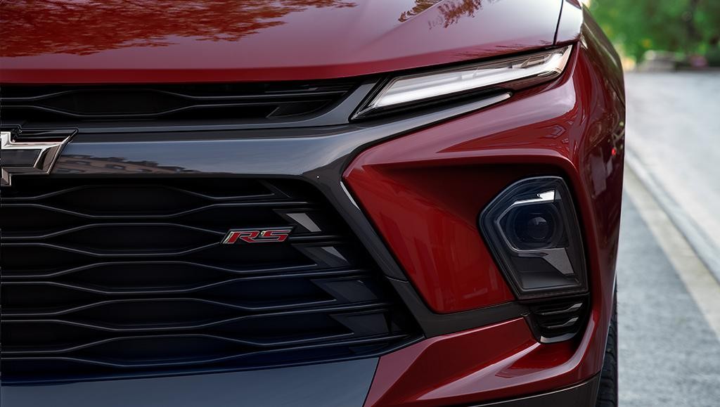 Close up of a red 2025 Chevrolet Blazer grille driving on the road