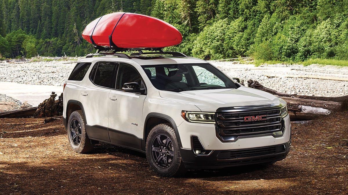 2020 GMC Acadia parked in a forest with lake in the background