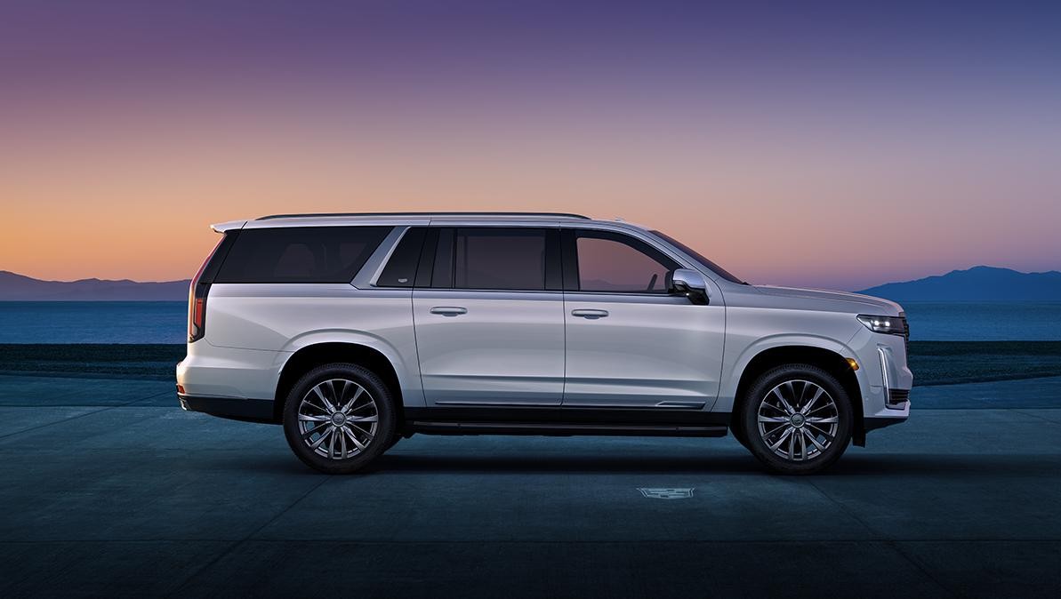 A white 2022 Cadillac Escalade parked on a desert salt flat at sunset.