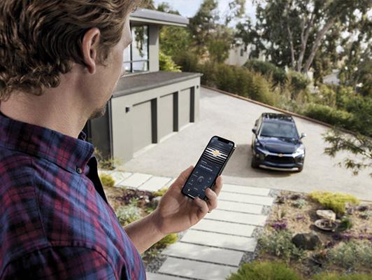 Man holding phone with myChevrolet App and Chevy in background Man holding phone with myChevrolet App and Chevy in background