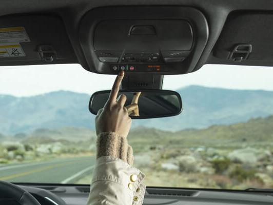 woman pushing onstar button on rear view mirror in desert woman pushing onstar button on rear view mirror in desert