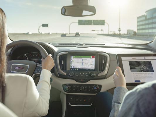 Woman driving using on screen navigation and man on tablet in passenger seat Woman driving using on screen navigation and man on tablet in passenger seat